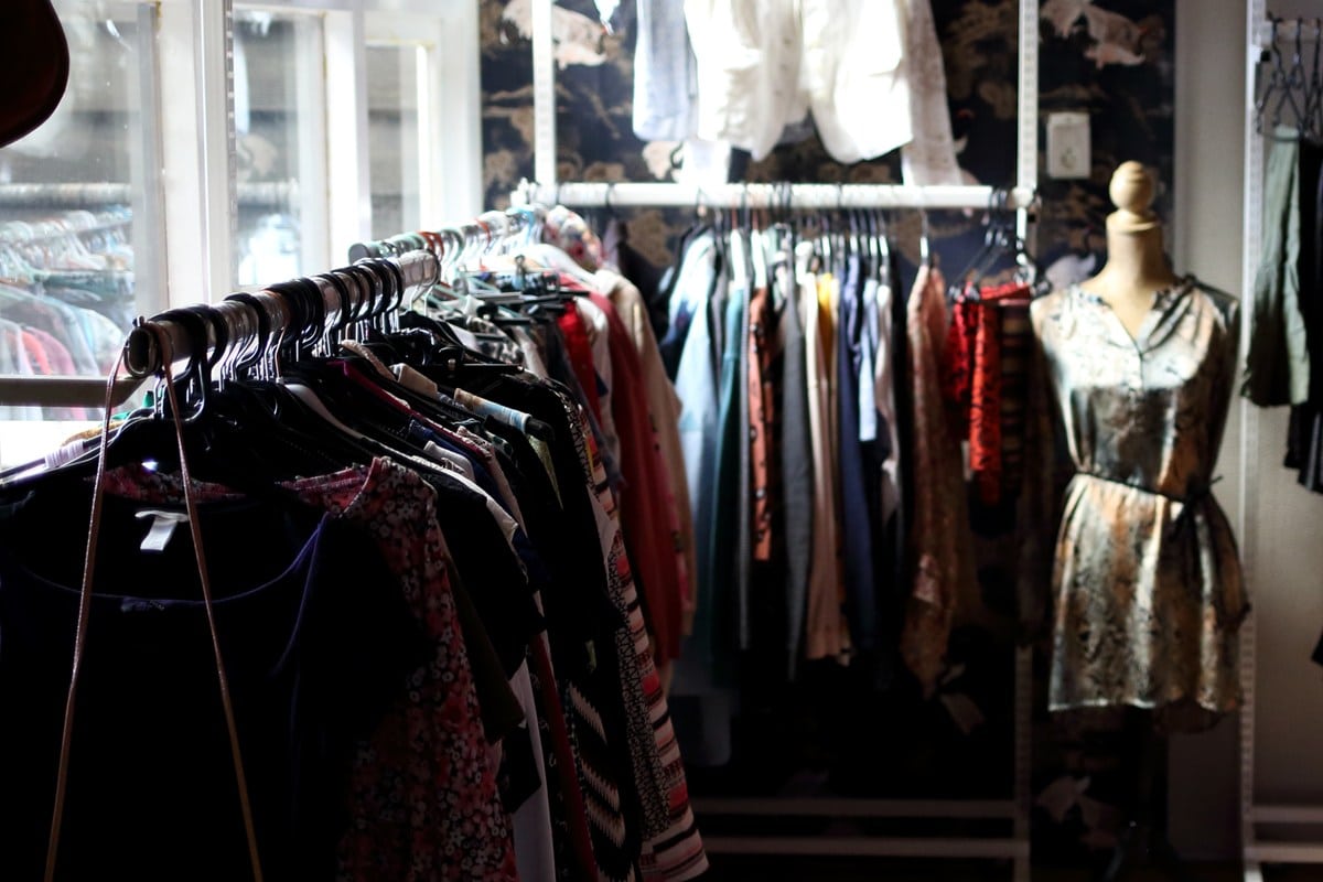 Kledingrek vol tweedehands kleding en een paspop in het Bloezem GGZ Inloophuis Nunspeet, onderdeel van een warme, uitnodigende kringloophoek.