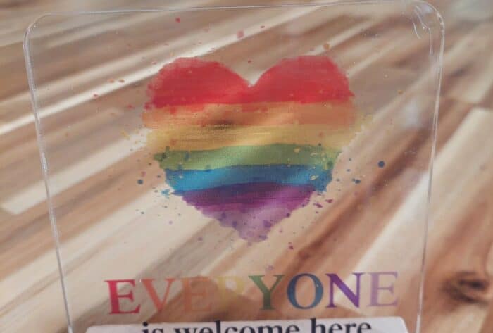 Op een houten tafel in een woonkamer staat de oorkonde van de Roze loper, een keurmerk dat laat zien dat we actief werken aan een inclusieve en veilige omgeving.